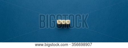 Wide View Image Of Brb Abbreviation Spelled On Wooden Dices. Placed Over Navy Blue Background.