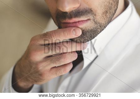 Elegant Young Handsome Man With A Beard In A White Classic Suit. The Hotels Interior. Photo Studio. 