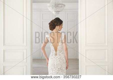 Beautiful Bride Posing In Wedding Dress In A White Photo Studio. Mirror. Sofa. Bouquet. The Door. Ch