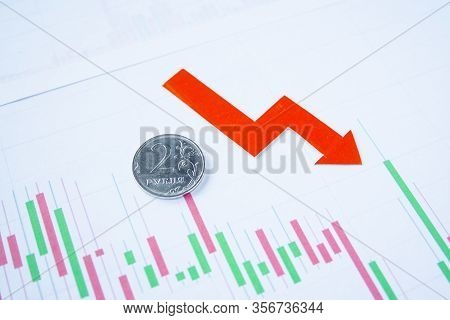 Two Rouble Coin On Currency Graph With Red Arrow Down. Exchange Rate Chart. Ruble Depreciation. Exch