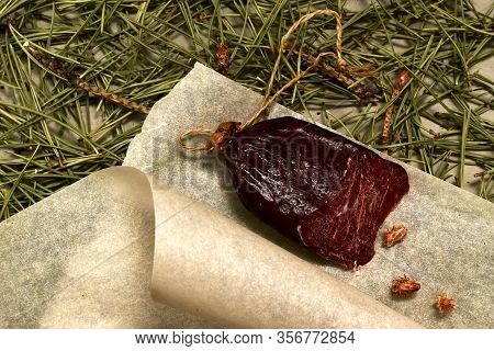 Dried Sausage Made Of Roe Deer Meat. Cut With Slices On Parchment With Pine Buds Closeup. Flooring M
