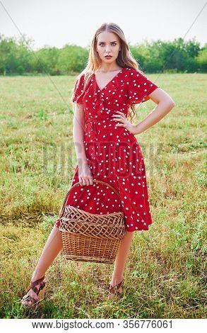 Outdoor Portrait Of The Beautiful Young Girl In Red Dress With Basket In Hand. Effect Of Old Film Wi