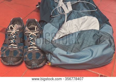 Hiking Equipment: Backpack And Trekking Boots On The Floor. Horizontal Photo And Brown Background. T