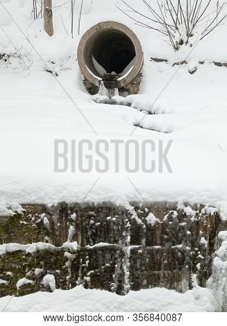 Concrete Run-off Pipe Discharging Water In Winter. Drain (drainage) Pipe In The Snow.