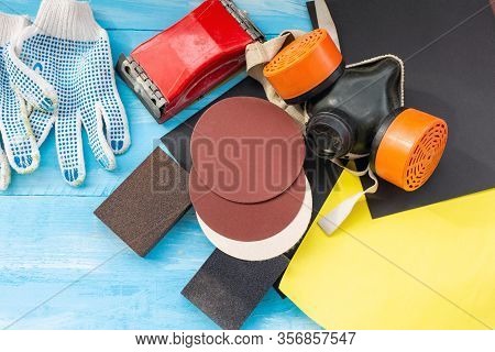 Abrasives, Sansing Paper And Sanding Sponges And Sanding Wheel Respirator On The Blue Wooden Backgro