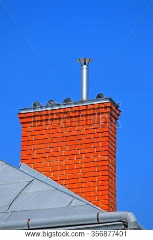 Orange Chimney Brick Pipe On The Roof On Blue Sky In Sunny Day, Modern Construction, Environment Pol