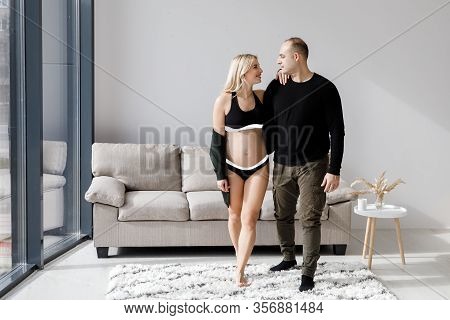 Couple Of Handsome Husband And Pretty Pragnant Woman Posing At Studio Embracing Stomach. Young Styli