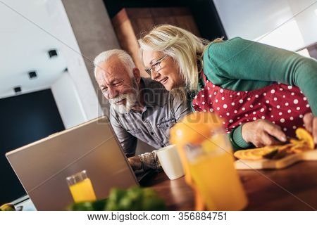 Happy Retired Couple Browsing The Internet Together On A Laptop Computer.quarantine. Health Concept.