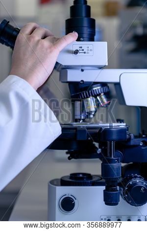 Scientific Handling A Light Microscope Examines A Laboratory Sample For Pharmaceutical Bioscience Re