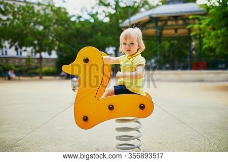 Adorable Toddler Girl Having Fun On Spring Rider On Playground. Outdoor Activities For Kids