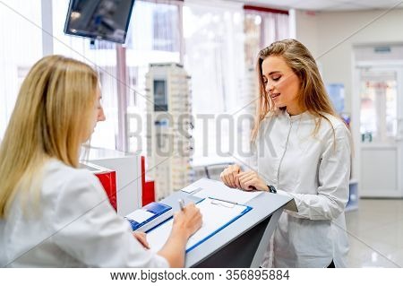 Writing A Prescription In Optics. Client And Doctor. Modern Shop With Ophthalmologist. Eye Health Ca