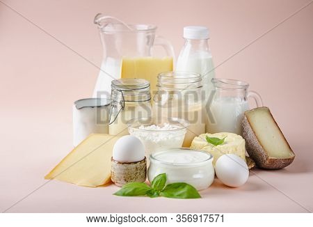 Fresh Dairy Products, Milk, Cottage Cheese, Eggs, Yogurt, Sour Cream And Butter On Pink Background