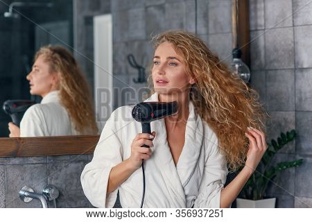 Charming Smiling Lady With Light Curly Hair In White Dressing Gown Looking At Her Reflection In The 