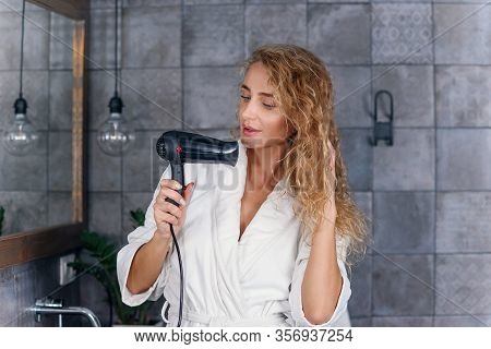 Charming Smiling Lady With Light Curly Hair In White Dressing Gown Looking At Her Reflection In The 