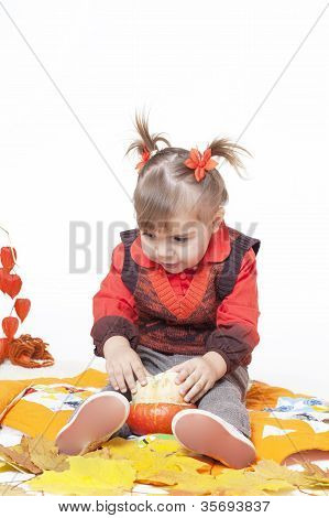 kleines MÃ¤dchen in einer orange Weste spielt mit groÃŸen KÃ¼rbisse