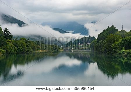 Beautiful River Landscape With Mountains, Green Trees And Low Clouds Or Fog. River In Kiso Valley, J