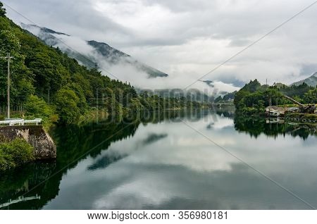 Beautiful River Landscape With Mountains, Green Trees And Low Clouds Or Fog. Kiso Valley, Japan