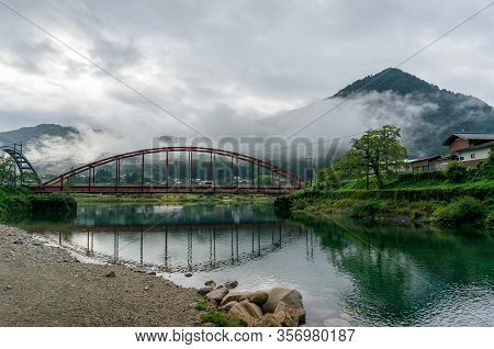 Red Bridge And River In The Mountain Valley. Japanese Countryside Landscape. Atera Valley In Kiso Va