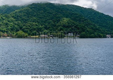 Lake Chuzenji And Mountains Landscape With Waterfront Buildings On The Backgorund