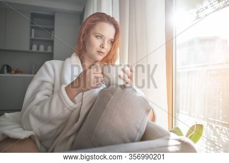 stayhome concept,  attractivewoman sitting in bed , holding cup of black coffee, enjoying peaceful calm weekend vacation morning time alone in bedroom at home or hotel.