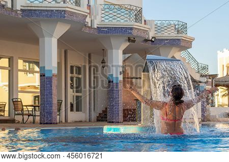 Woman Enjoying Under Jet Of Hydromassage Water With Gentle Splashes At Spa Resort. Waterfall Flow In