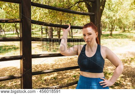 Portrait Of A Young Female Athlete Leaning On A Public Trellis Outside. Athlete Practising Sport Out