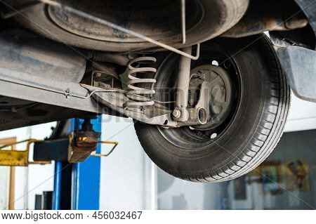 Fragment Of The Rear Wheel Of A Car On A Lift In A Car Repair Shop. Low Viewing Angle. Close-up