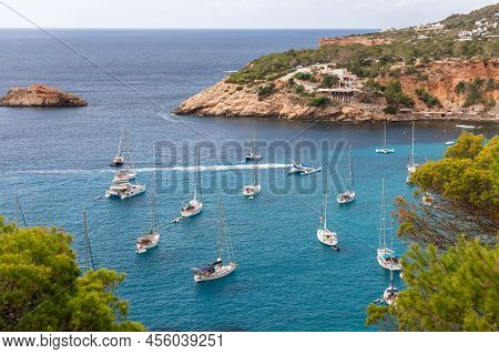 Aerial View Of Crystal Clear Turquoise Water Of Bay Port Brut At Cala D'hort With A Few White Sailin