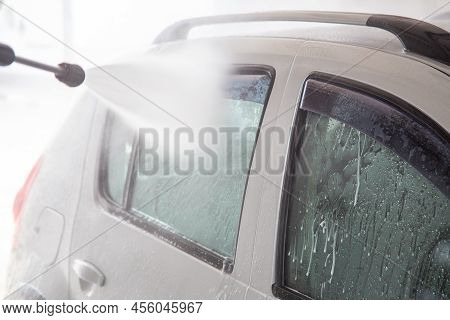 A Process Of Flushing Soap Sud On Silver Car Windows With Pressurised Water Stream At Self-service I