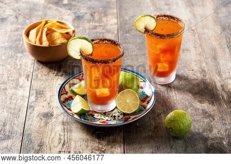 Homemade Michelada Cocktail With Beer, Lime Juice,hot Sauce,salted Rim And Tomato Juice On Wooden Ta