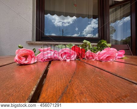 Eight Freshly Cut Pink Roses And One Red Rose Are Lying On The Table