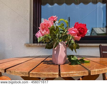 Eight Freshly Cut Pink Roses And One Red Rose Are Lying On The Table