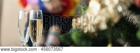 Close-up Of Two Glasses Near Decorated Christmas Tree And Sad Woman Sitting Alone. Broke Up With Gir