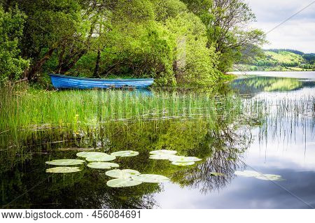 Old Blue Row Boat On A Calm Lake In Ireland