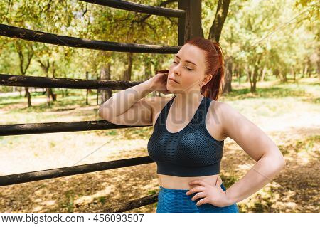 Young Woman Athlete, Resting After Training On An Outdoor Trellis. Athlete Practising Outdoor Sport.