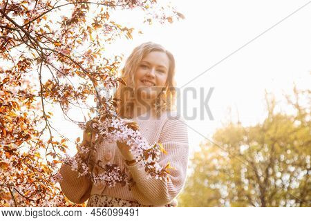 Portrait Of Young Woman With Fair Hair Wearing Pink Cardigan, Dress Standing Near Blossoming Bird-ch
