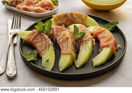 Honeydew Melon With Fresh Mint And Prosciutto Ham. Gourmet Snack, Sweet-savory Tasty Appetizer.