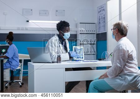 Clinic Radiologist Showing Radiogram To Sick Elderly Patient And Recommending Medical Procedure. Hos