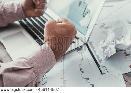 Close Up Of Man Punches Against Charts On Paper And Computer Display. Concept Of Stock Forex Market 