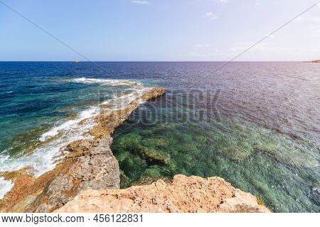Widescreen Shot: Narrow Strip Of Rocky Coast Goes Deep Into Sea Forming Small Bay With Clear Transpa