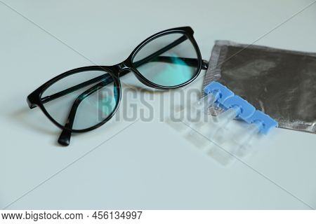 Single Dose Eye Drops And Glasses On White Table, Closeup
