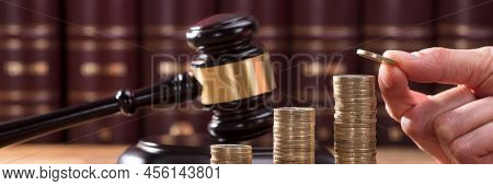 Close-up Of Human Hand Placing A Coin On Increasing Stacked Coins