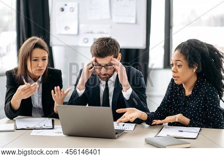 Irritated Business Employees Of A Different Nationalities Are Sitting At The Workplace In A Modern O