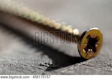 Selective Focus, Macro Photography Of A Tapping Screw With A Cross Head Screwdriver , Wooden Backgro