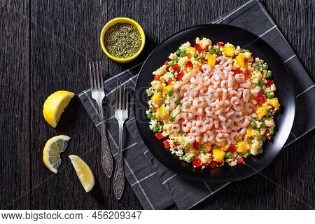 Cooked Small Pink Shrimps Topped Over Millet Pilaff With Vegetables, Mango Chunks And Spices On Blac