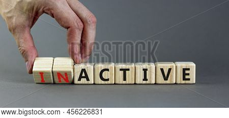 Active Or Inactive Symbol. Businessman Turns Wooden Cubes And Changes The Word Inactive To Active. B
