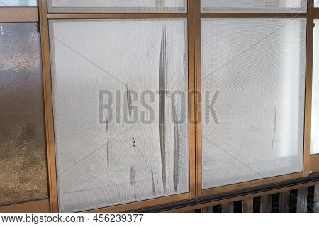 Ripped  Screen Door Beside Glass Door On The Open Corridor