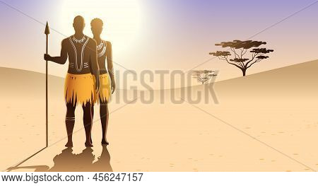 Aborigine Couple With Body Art And Ethnic Dress, Standing On A Sandy Landscape And Holding A Spear.