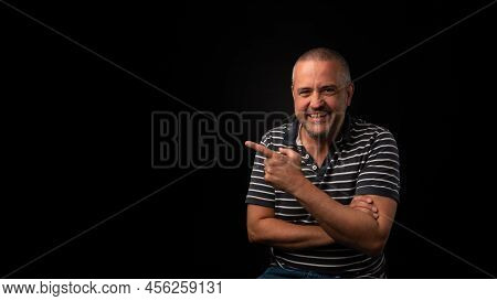 A Smiling Man Pointing On A Black Background With Copy Space