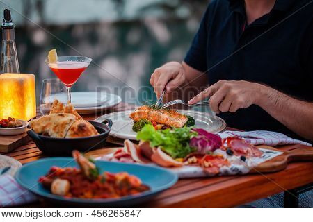 Man On Luxury Dinner Served On Table With Fresh Seafood, Cold Cuts And Cocktail Glass In Luxury Outd